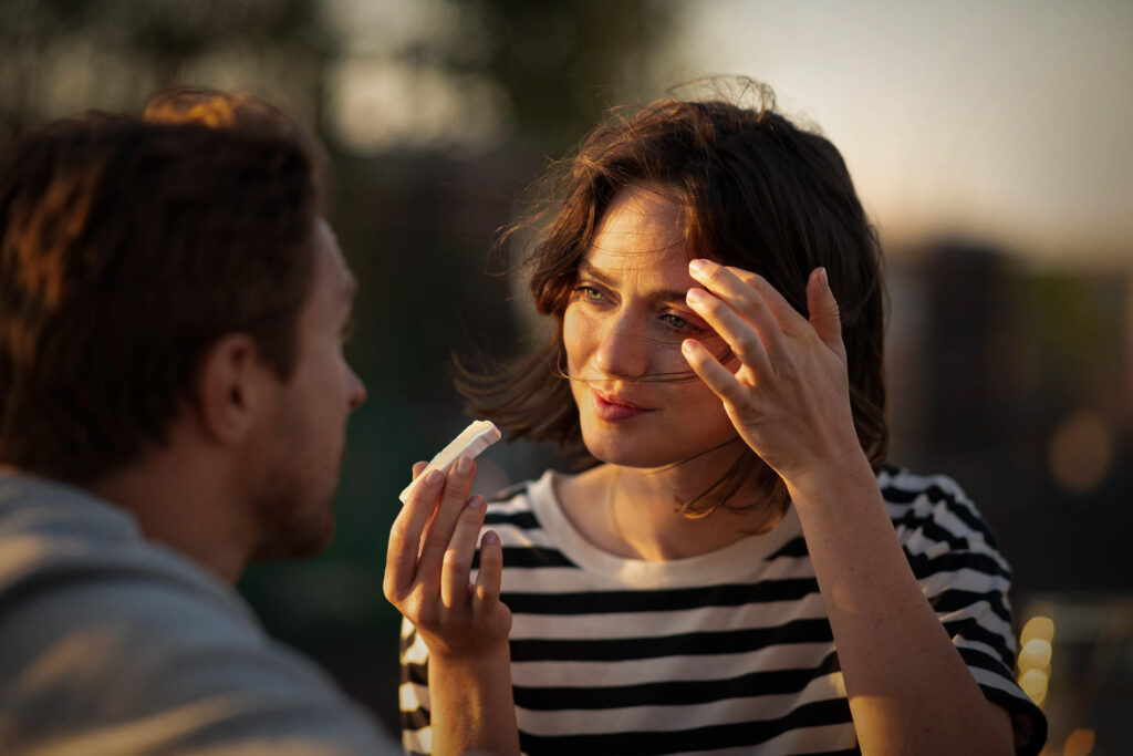 Französische Frau spricht mit Mann, hält ein Stück Geramont-Käse in der Hand – authentische, ungestellte Lifestyle-Werbefotos bei Sonnenaufgang für Geramont.
