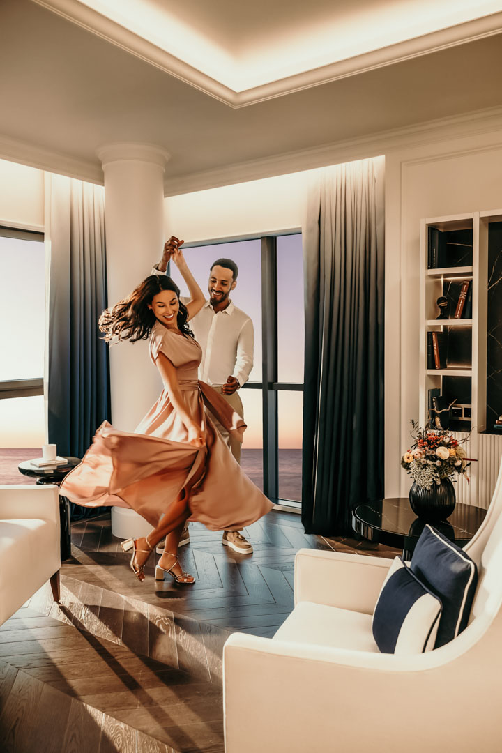 Dieses Bild zeigt eine Frau in einem rosafarbenen Schlafanzug, die entspannt in einem Bett liegt, umgeben von weißen Kissen und Bettwäsche, im Sofitel Hotel Barcelona. Die Szene vermittelt Luxus, Komfort und Ruhe – ideal für Werbefotos, Hotel-Marketing, Social Media oder Website-Header im Premium-Hospitality-Segment. Die hochwertige, stimmungsvolle Bildsprache entspricht dem Stil eines professionellen Werbefotografen aus Berlin und transportiert exklusive Hotelatmosphäre, Wohlbefinden und Lifestyle. Tanzendes Paar vor Meerblick im französischen Zimmer des Sofitel Barcelona – Hotelfotograf aus Hannover erstellt Lifestyle-Werbefoto und Businessfoto