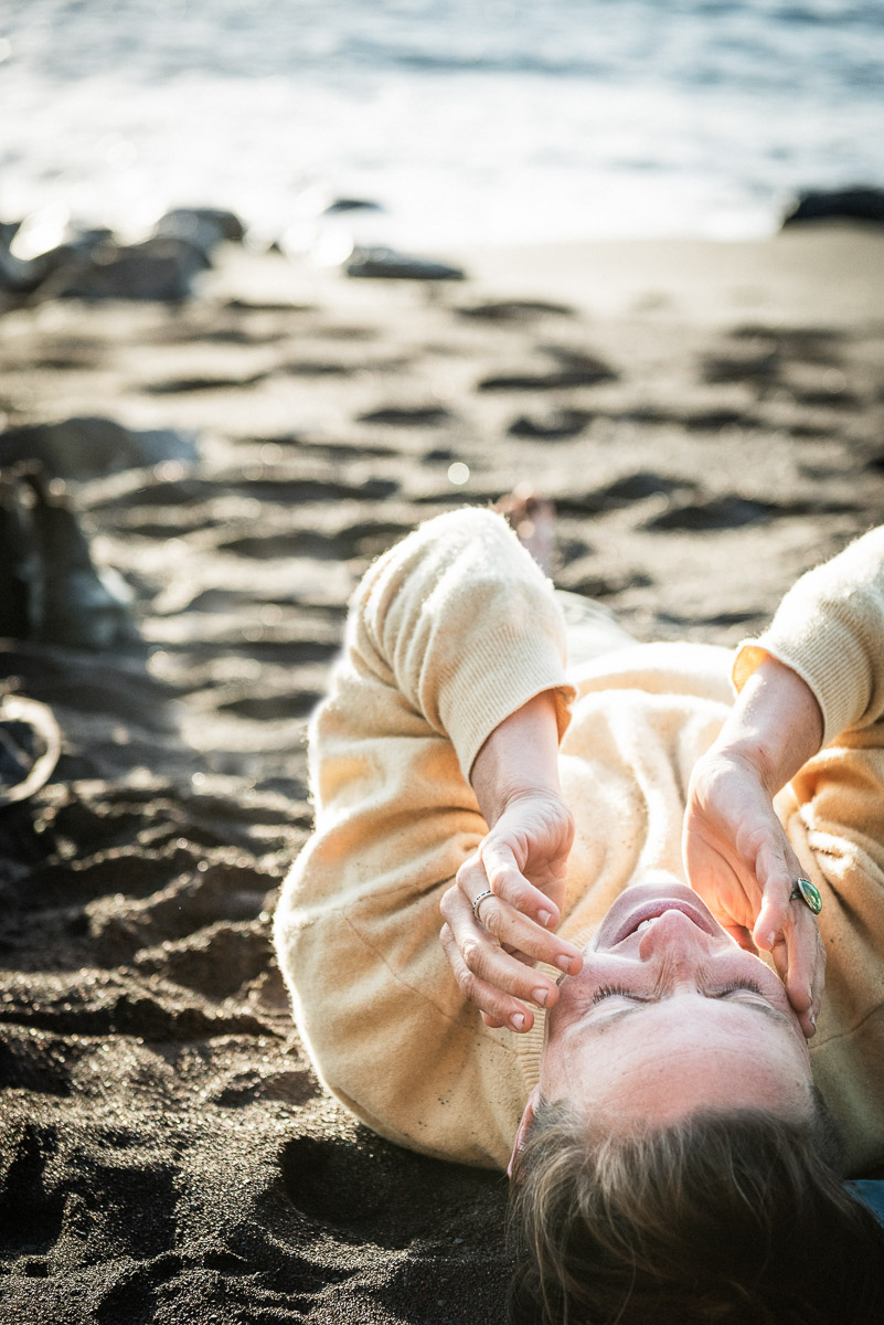Frau liegt entspannt am Strand - ruhige portraitfotografie in einer abgelegenen Küstenlandschaft